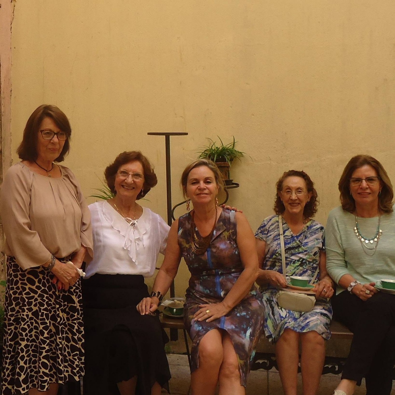 Cinco amigas da Roda posando juntas em frente a uma parede amarela