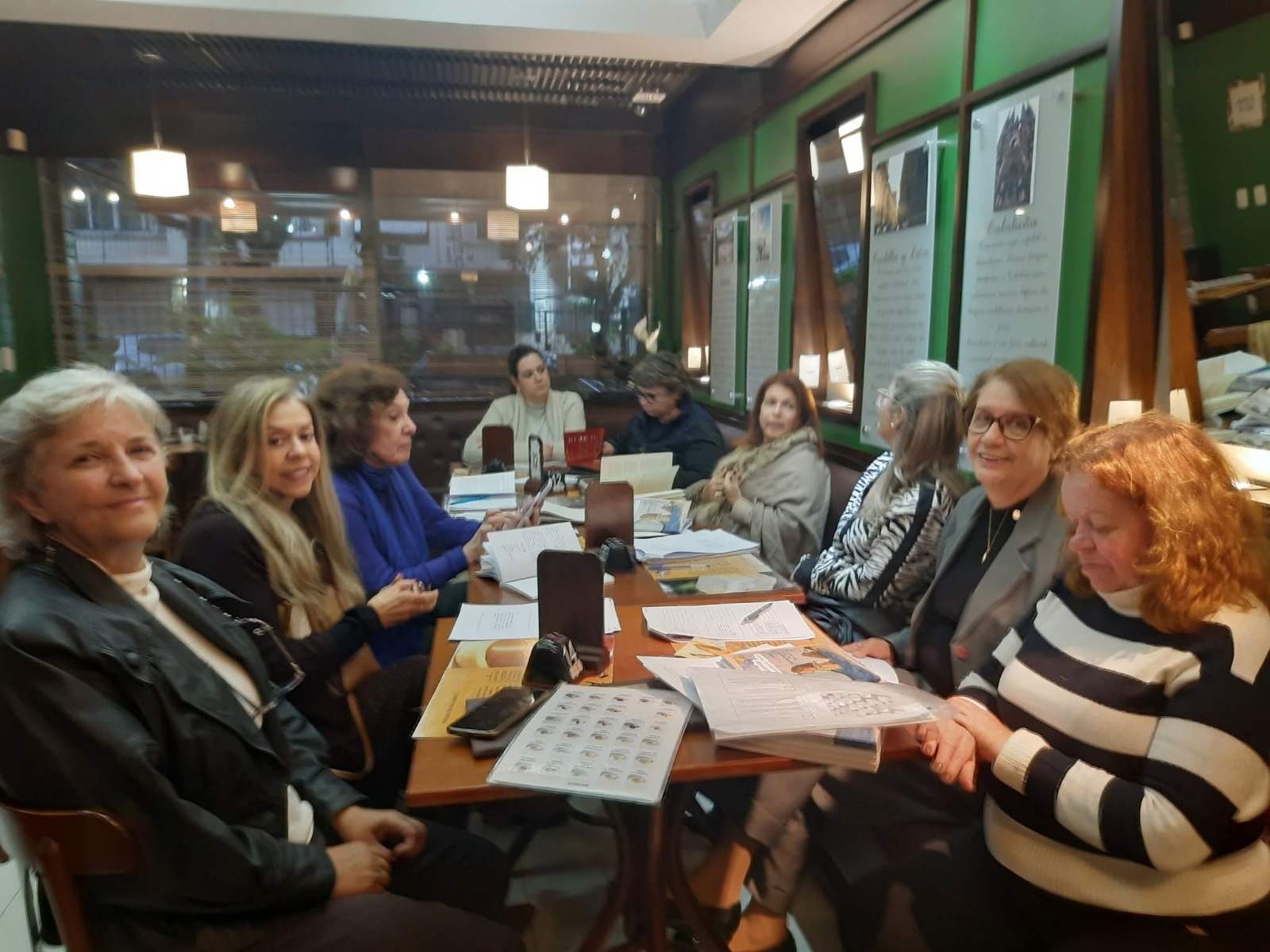 Encontro da Roda em torno de uma mesa, em ambiente com paredes verdes e luzes pendentes